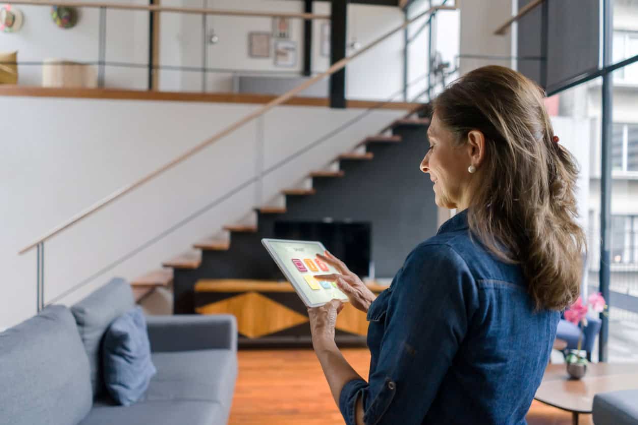 Femme controlant l'ambiance de sa maison via la domotique