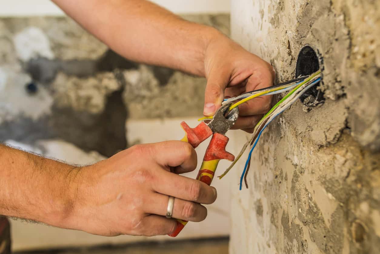 Mains d'electricien coupant des fils avec une pince